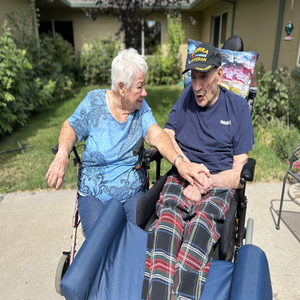 An elderly female and elderly male in wheelchairs smiling