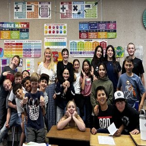Students and a teacher in a classroom, smiling