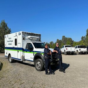 Two EMT workers standing in front of an ambulance